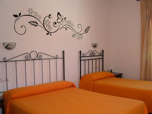 - une chambre avec 2 lits avec des draps orange dans l'établissement Hotel Cortijo Los Gallos, à Chiclana de la Frontera