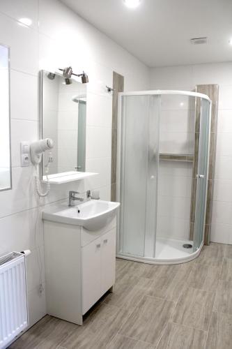 a white bathroom with a shower and a sink at Panorama Apartments in Karlovy Vary