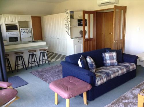 a living room with a blue couch and a kitchen at Darfield Bel Air right on the main street in Darfield