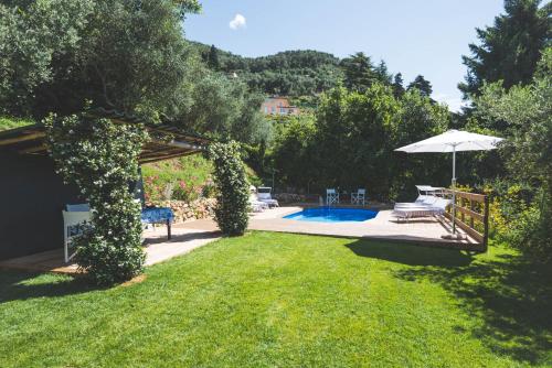 a backyard with a pool and an umbrella at Exclusive beautiful pool house surrounded by greenery, modern, luxury finishes in Camaiore