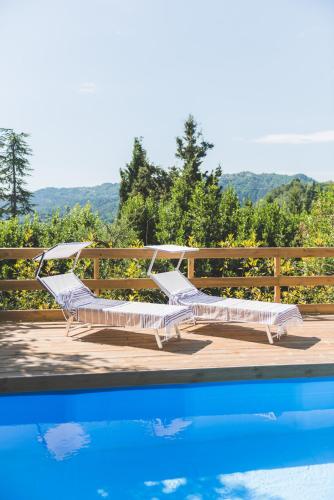 a couple of white lounge chairs next to a pool at Exclusive beautiful pool house surrounded by greenery, modern, luxury finishes in Camaiore