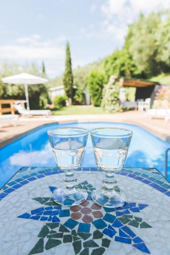 two wine glasses sitting on a table next to a pool at Exclusive beautiful pool house surrounded by greenery, modern, luxury finishes in Camaiore