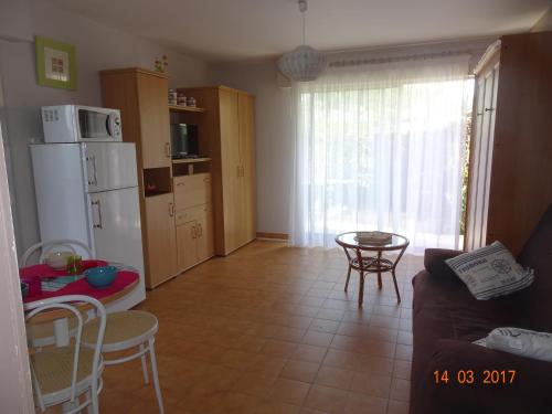 - un salon avec un réfrigérateur, une table et des chaises dans l'établissement RESIDENCE LES ECUREUILS, à Saint-Palais-sur-Mer