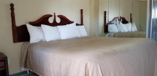 1 dormitorio con 1 cama grande con almohadas blancas en Maxim III Motel, en Houston