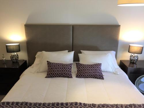 a bedroom with a large white bed with two lamps at URBANA SUITES & STUDIOS 440 in San Carlos de Bariloche