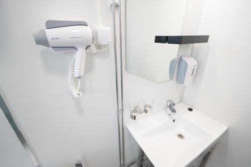 La salle de bains est pourvue d'un lavabo blanc et d'une douche. dans l'établissement Hotel Citi Inn, à Tampere