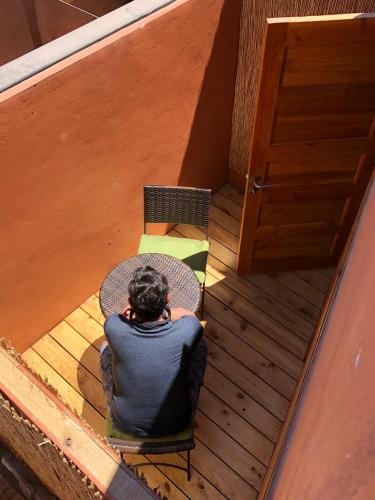 a man sitting on a chair in front of a table at Hotel Casa Algarrobo in San Pedro de Atacama