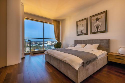 a bedroom with a large bed and a large window at Luxury Panoramic Vilnius apartment in Vilnius