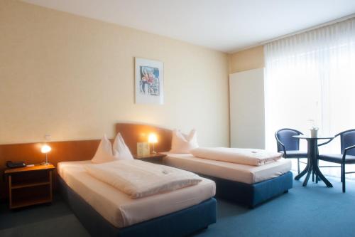 a hotel room with two beds and a table at Hotel Stadt Püttlingen in Püttlingen