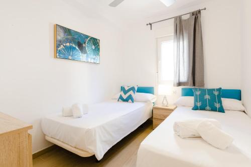 dwa łóżka w pokoju z białym i niebieskim w obiekcie Picasso Daisy w mieście Fuengirola