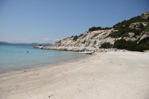 a boat sitting on a sandy beach near the water at Hotel Le Dune in Porto Pollo