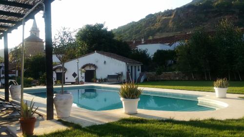 une piscine avec des plantes en pot en face d'une maison dans l'établissement Casona Del Duende, à Alájar