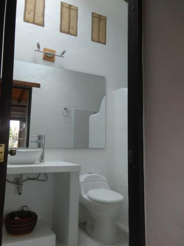 a white bathroom with a toilet and a sink at Casa Tzabar in Villa de Leyva