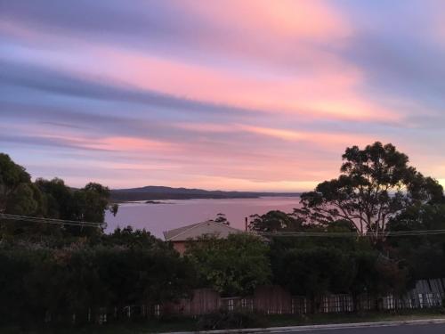 a view of a body of water with a sunset at GRANITE BEACH HOUSE @ Bay of Fires in Binalong Bay