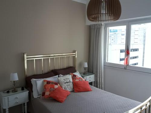 Un dormitorio con una cama con almohadas rojas y una ventana en Departamento Miramar en Miramar