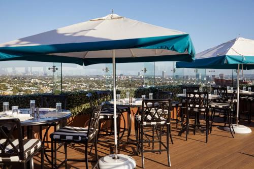 a group of tables and chairs with umbrellas on a roof at The London West Hollywood at Beverly Hills in Los Angeles