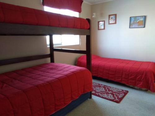 a bedroom with two bunk beds with red sheets at Condominio Laguna Vista Camino Casablanca 788 Algarrobo in Algarrobo