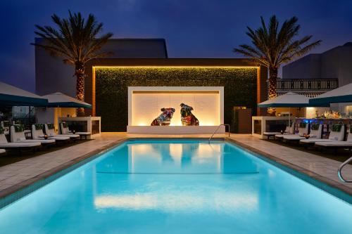 a swimming pool at night with two dogs in a window at The London West Hollywood at Beverly Hills in Los Angeles