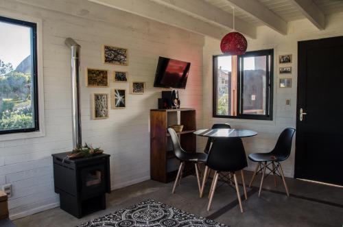 Habitación con mesa, sillas y TV. en Norwood Eco Cabañas, en Punta del Diablo