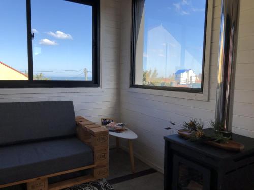 a living room with a chair and two windows at Norwood Eco Cabañas in Punta Del Diablo