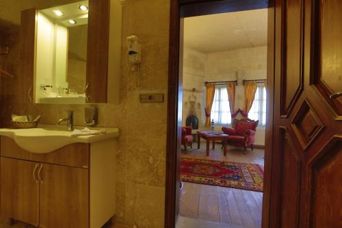 a bathroom with a sink and a mirror and a living room at Vezir Cave Suites in Goreme