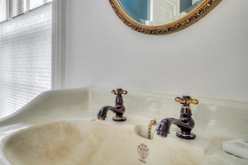 a bathroom sink with two faucets and a mirror at The Water Street Inn in Kittery