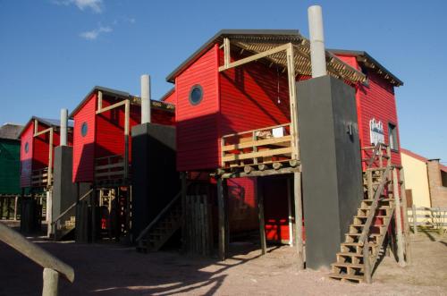 a red house with a staircase in front of it at Norwood Eco Cabañas in Punta Del Diablo