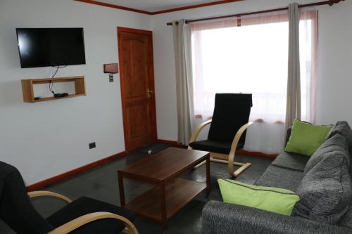 a living room with a couch and chairs and a tv at Terrazas de Nercon in Castro