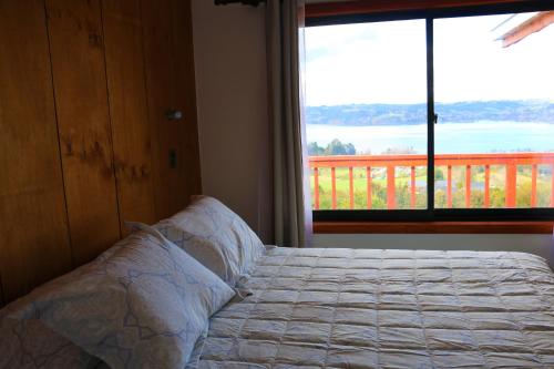 ein Schlafzimmer mit einem Bett und einem großen Fenster in der Unterkunft Terrazas de Nercon in Castro