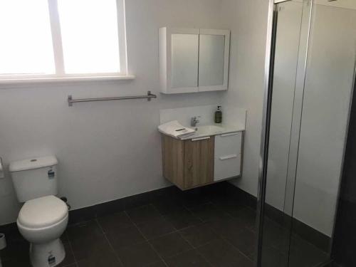 a bathroom with a toilet and a sink and a shower at Maddington House Unit A in Perth