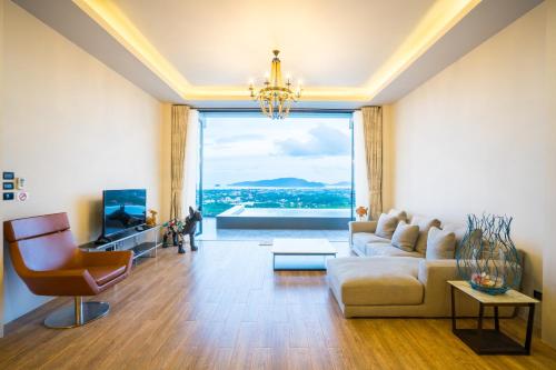 a living room with a couch and a large window at Nakara Hill Phuket in Chalong