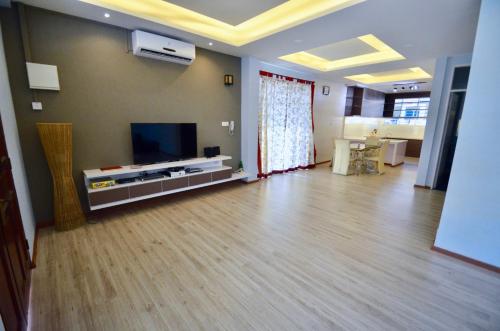 a living room with a flat screen tv and a wooden floor at Sandakan Puteri Indah House in Sandakan