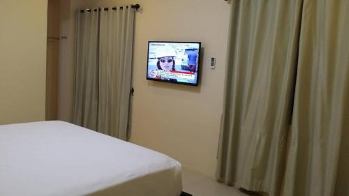 a bedroom with a bed and a television on a wall at Villa Del Faro in Batangas City
