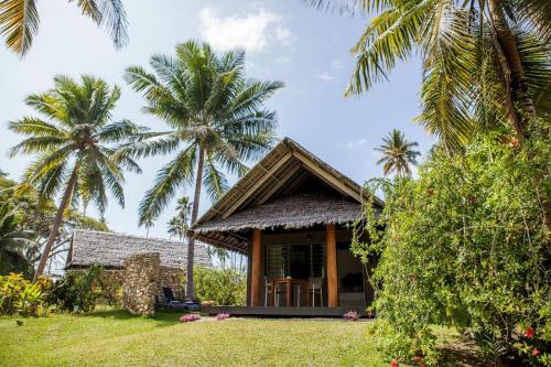 a house with palm trees in front of it at Aore Island Resort in Luganville