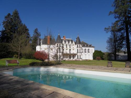 a large white house with a swimming pool in front of it at Château de la Motte in Noailly