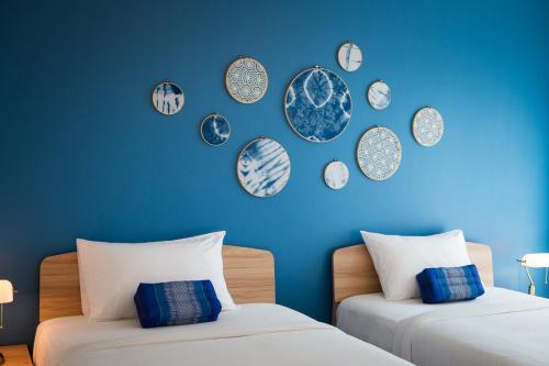 two beds in a room with clocks on the wall at DeeProm Pattaya Hotel in Pattaya Central