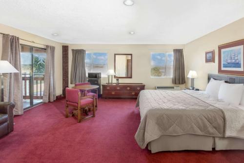 a hotel room with a bed and a table and chairs at Days Inn by Wyndham Jackson in Jackson