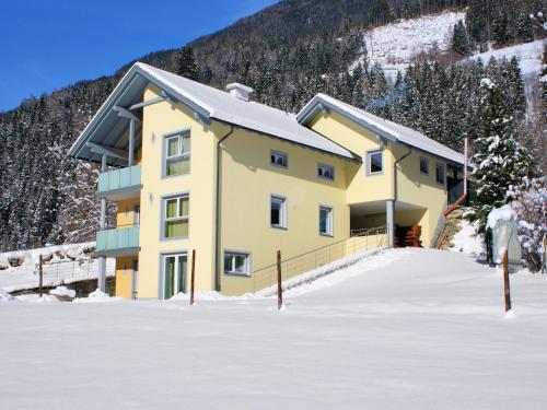 a yellow building in the snow with a mountain at Appartementhaus Monika in Flattach