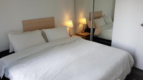 a bedroom with a large white bed with two lamps at 2 bedrooms CBD FREE Tram apartment (Melb Central, China Town, Queen Victoria Market, Melbourne University, RMIT, etc) in Melbourne