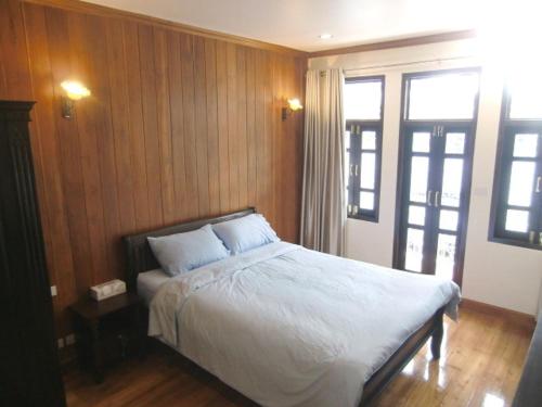 a bedroom with a bed with white sheets and a window at The Royal ThaTien Village in Bangkok