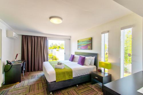 Cette chambre comprend un lit et un bureau. dans l'établissement Mackay Oceanside Central Hotel Official, à Mackay