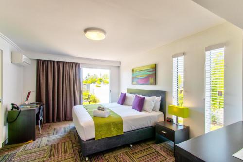 ein Hotelzimmer mit einem Bett und einem Schreibtisch in der Unterkunft Mackay Oceanside Central Hotel Official in Mackay
