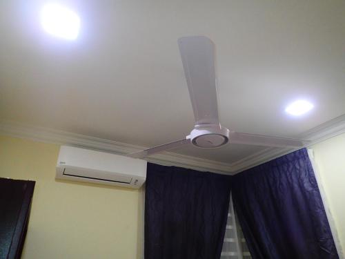 a ceiling fan in a room with a blue curtain at RizQin Homestay Bachok in Bachok
