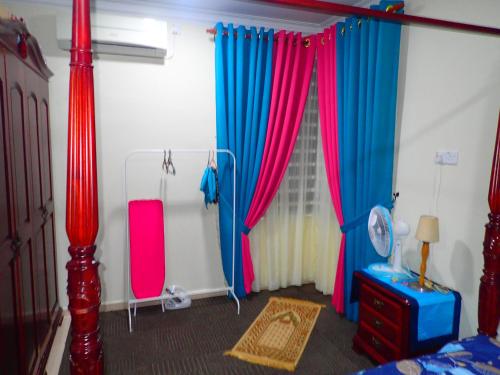 a bedroom with red and blue curtains and a bed at RizQin Homestay Bachok in Bachok