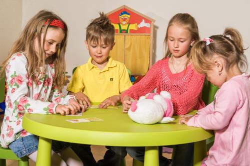 three children sitting around a table playing with toys at GRUBERS, Hotel Appartments Gastein in Bad Gastein