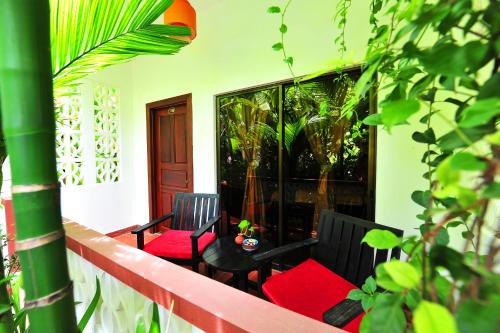 a balcony with two chairs and a table with red cushions at La Niche D'angkor Boutique Hotel in Siem Reap