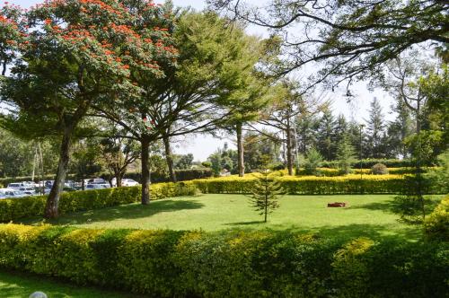 a park with trees and bushes and a green lawn at Golf Hotel Kakamega in Kakamega