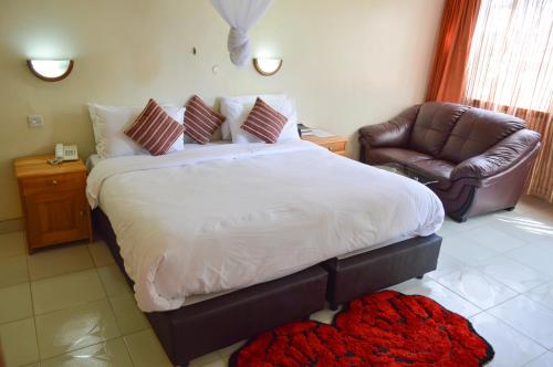a bedroom with a large bed and a leather chair at Golf Hotel Kakamega in Kakamega