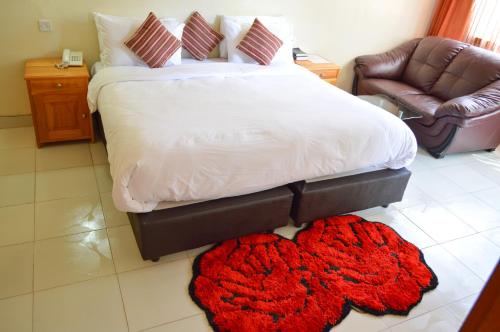 a bedroom with a bed with a red rug on the floor at Golf Hotel Kakamega in Kakamega