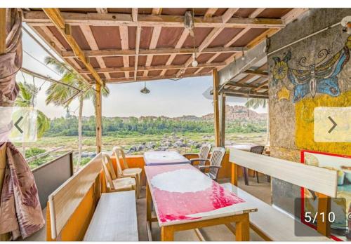 una sala da pranzo con tavolo, sedie e vista di Archana Guest House River View a Hampi